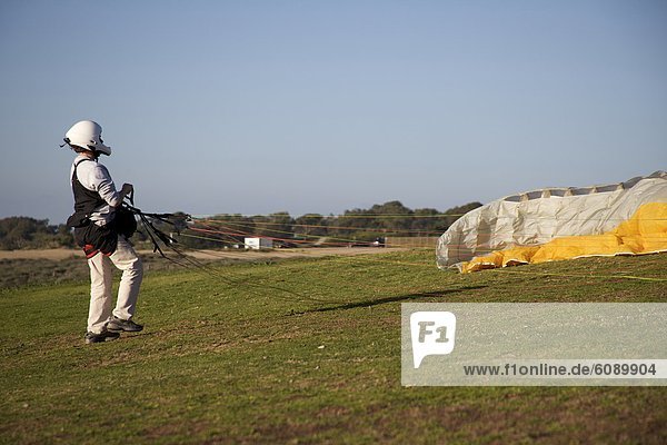 Female sets her parachute on the grass at the paragliding port in Torrey Pines  San Diego  California.