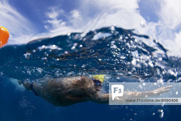 Underwater view of a swimmer rounding a bouy during an annual ocean swimming race in the tropical waters off of Mana Island  Fiji.