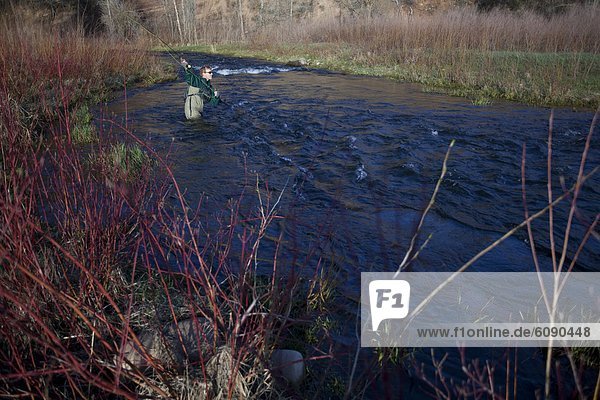 A man casts as he fly fishes at sunrise in the early spring on the Provo River  Utah.