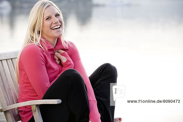 A young woman hanging out on a dock over Lake Washington and smiling at camera.