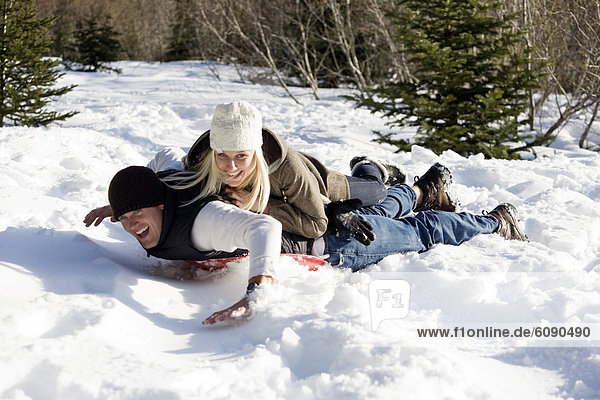 A man and woman enjoy a day of sledding activities in the mountains.