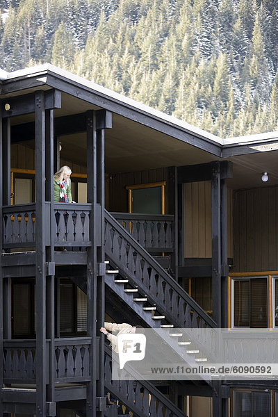A man and woman communicate from different floors at a mountain lodge.