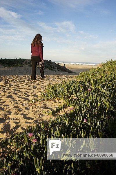 A women walking on the sand at Pismo Beach.