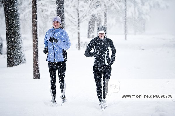 Two women run down Mountain Avenue in a snowstorm.