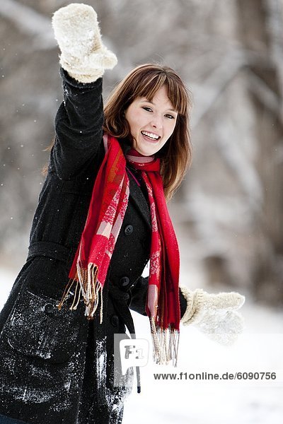 A woman wears a red scarf and throws a snowball on an overcast winter day  in Fort Collins  Colorado.