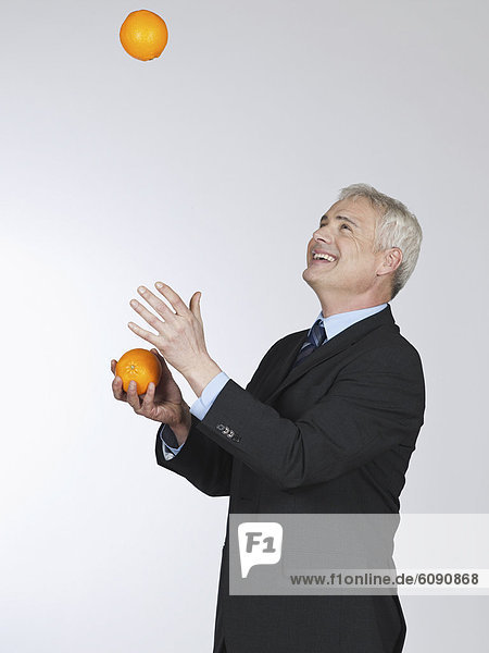 Mature man juggling with oranges