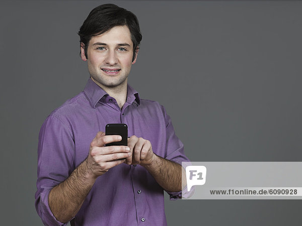 Young man using mobile phone  smiling  portrait