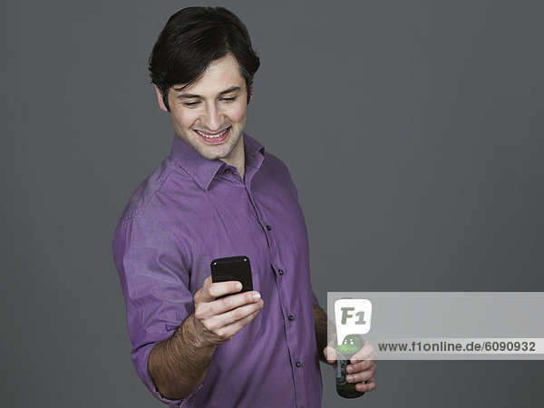 Young man with beer bottle and mobile phone  smiling