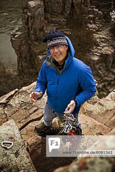A man holds climbing gear and smiles in Palisades State Park  South Dakota.