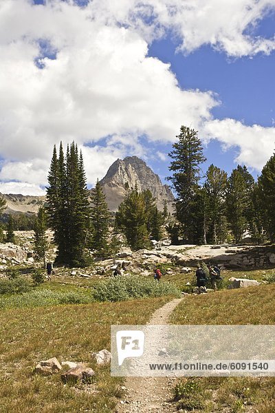 Hikers backpack through Alaska Basin with Buck Mountain in the background during a summer trip through Grand Teton National Park.