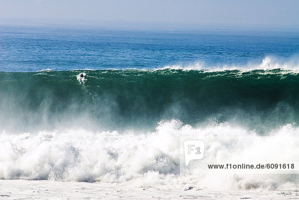 A surfer paddles over a giant wave at Blacks Beach in San Diego  California.