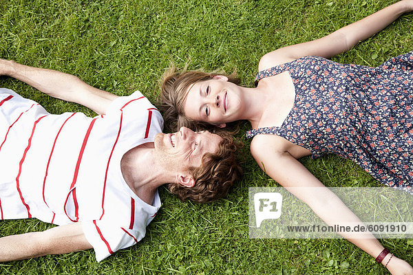Man and woman lying on grass in allotment garden