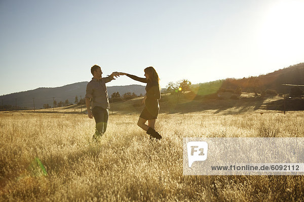 Happy couple dancing in an open field.