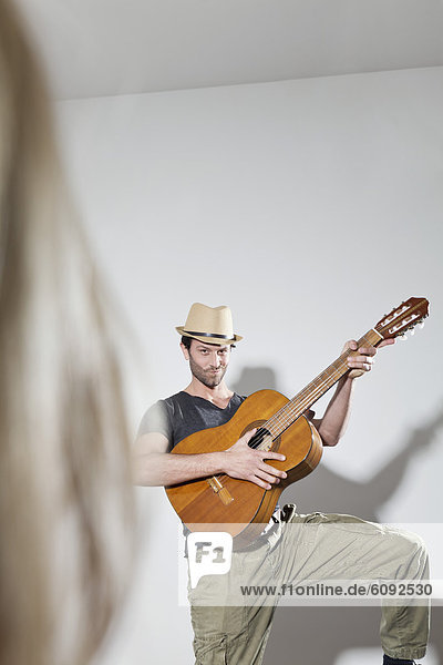 Mann zupft Gitarre  lächelnd