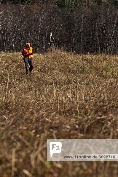Older man bird hunting in a field.