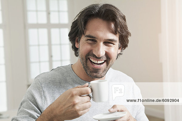 Erwachsener Mann mit Kaffeetasse  lächelnd  Portrait