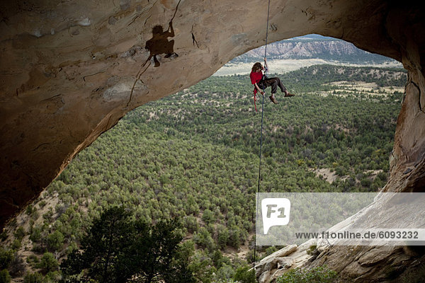 Young adult male rappels down an arch in Colorado.