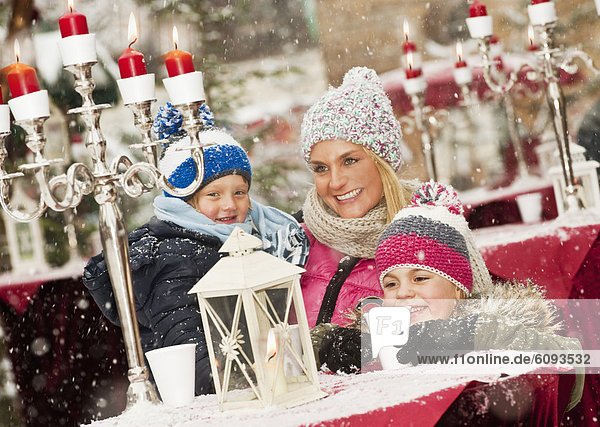 Österreich  Salzburg  Mutter mit Kindern auf dem Weihnachtsmarkt  lächelnd
