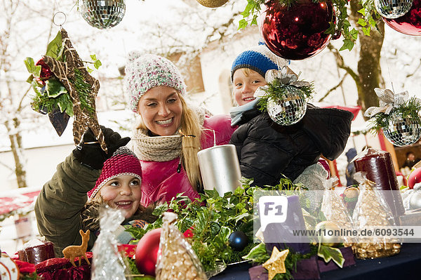 Österreich  Salzburg  Mutter mit Kindern auf dem Weihnachtsmarkt  lächelnd