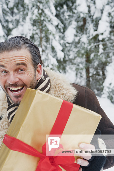 Österreich  Salzburger Land  Erwachsener Mann stehend mit Weihnachtspäckchen  lächelnd  Portrait
