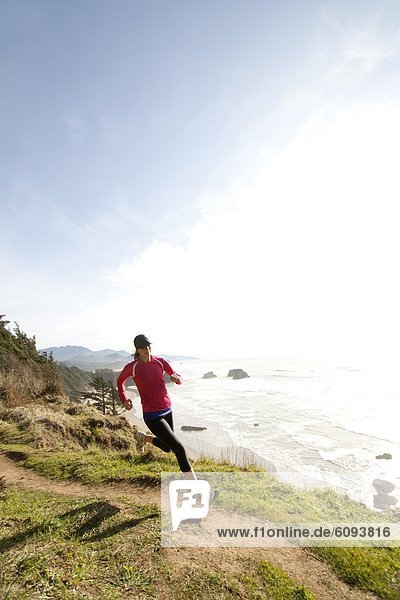 Woman trail running along the Oregon coast.