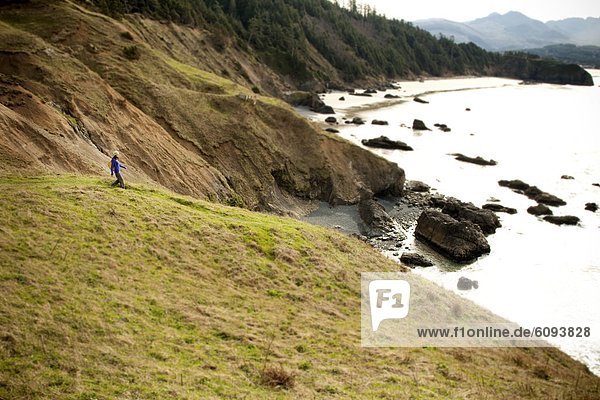 A woman hiking along a trail leading to the Pacific Ocean.