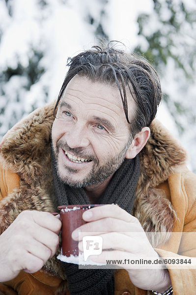 Österreich  Salzburger Land  reifer Mann trinkt Tee  lächelnd