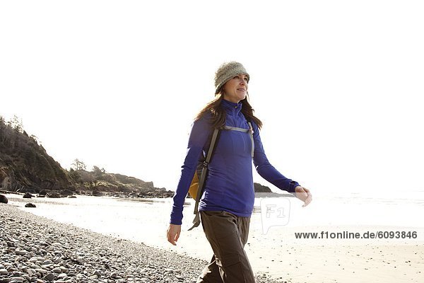 A woman hiking a secluded rocky beach.