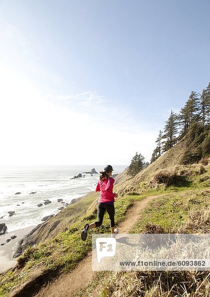Woman trail running along the Oregon coast.