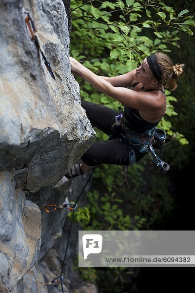 Female American climbing blocky limestone cliff.
