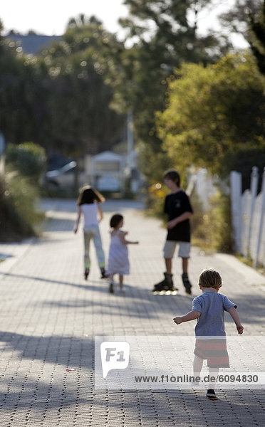 A group of kids are roller blading and walking down an alley.