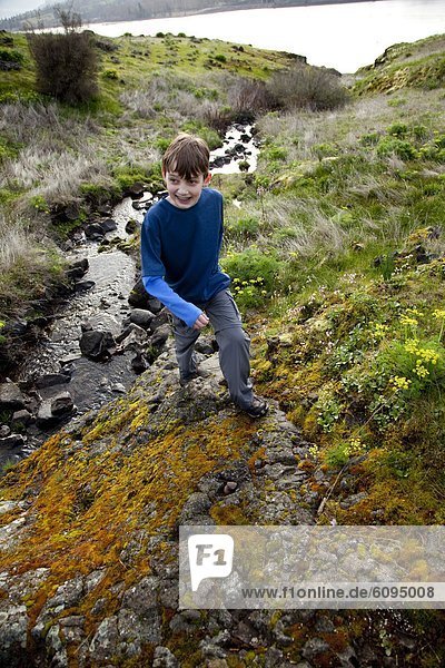 A young boy hiking along a stream.