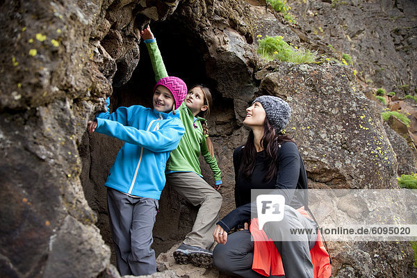Two daughters and their mother exploring a cave.