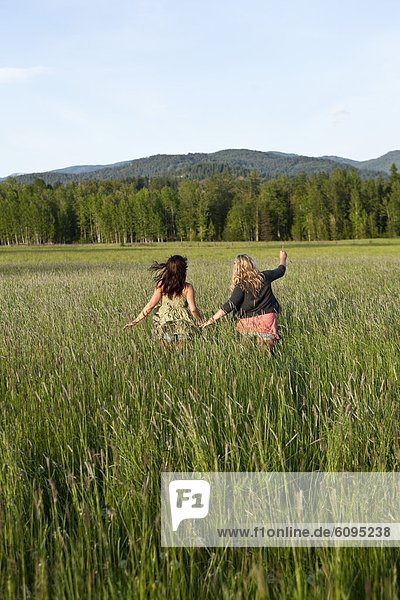 Girls walk through a grassy field in Sandpoint  Idaho.