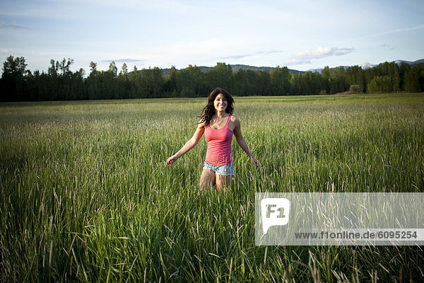 A girl twirls through tall grass on a sunny day in Idaho.