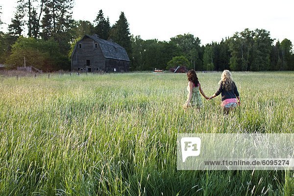 Girls walk through grassy field in Sandpoint  Idaho.