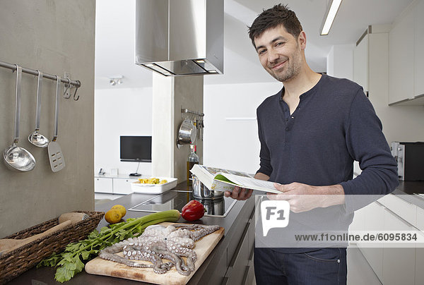 Mid adult man with cook book in kitchen  portrait