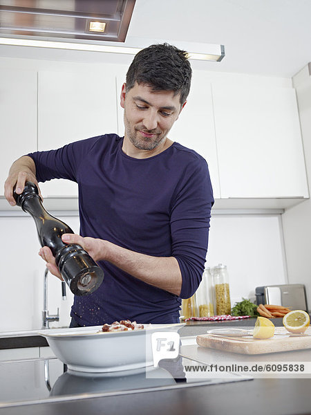 Mid adult man cooking food in kitchen