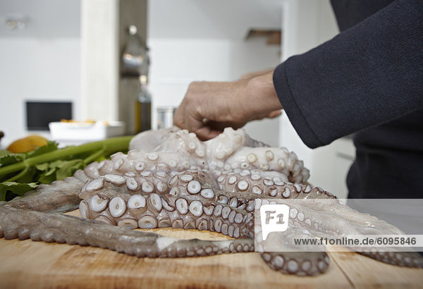 Mid adult man preparing octopus in kitchen