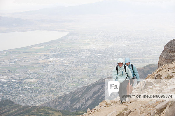 Two female hikers near the summit of Mt. Timpanogos  with the city of Pleasant Grove  UT in the background.