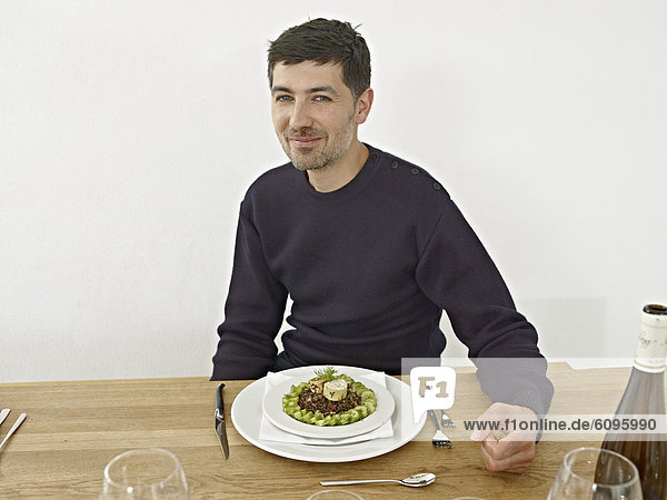 Mittlerer Erwachsener Mann beim Abendessen in der Küche  lächelnd  Portrait