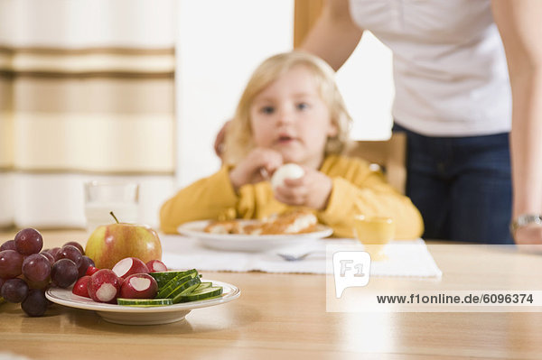 Frische Früchte auf dem Tisch  Mädchen beim Frühstück im Hintergrund