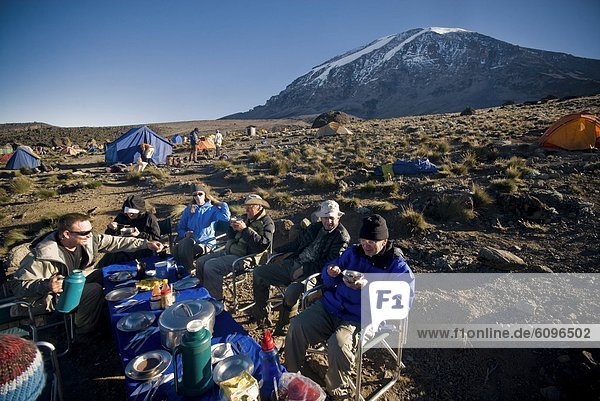A team of hikers have a nice breakfast at sunrise about 1000 ft. below the summit of Mt. Kilimanjaro.