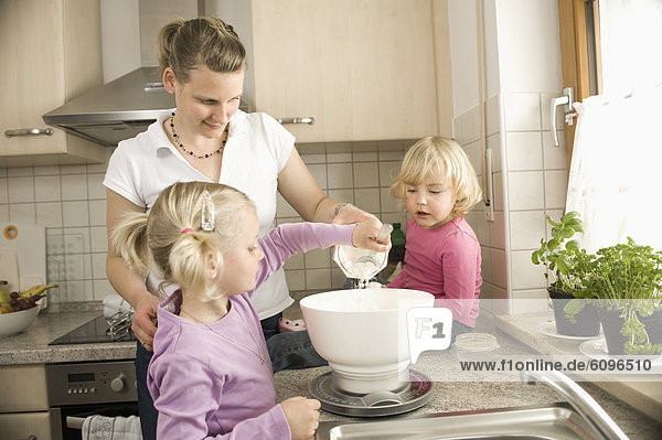 Mother and daughter preparing cake in kitchen