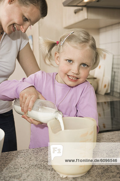 Mother and daughter pouring milk into measuring cup