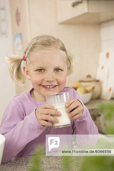 Girl drinking glass of milk  smiling  portrait