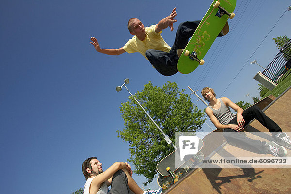Three skateboarders doing tricks at a skate park.