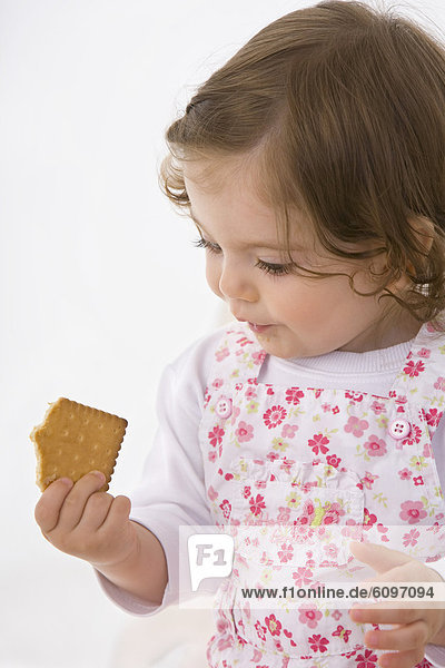 Kleines Mädchen schaut sich den Keks an