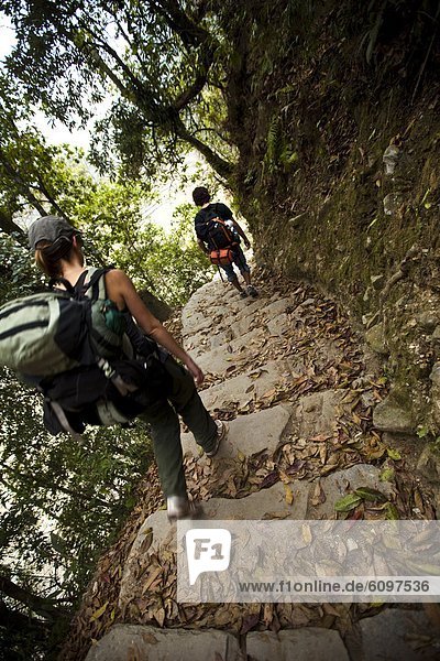Two trekkers descending stone steps in Nepal.