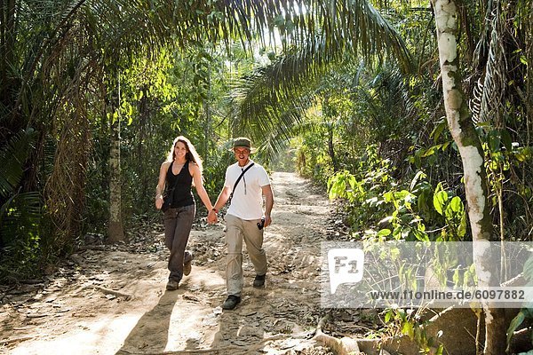 Recent  young  newlyweds enjoy themseleves while walking down a path in the amazon rainforest.